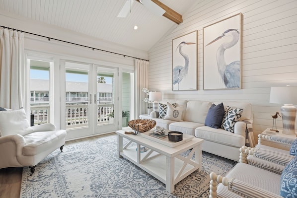 A spacious living room with a white sofa, a coffee table, and a patterned rug. - The Lady Cora | Canal Views + Community Pool (Rockport)