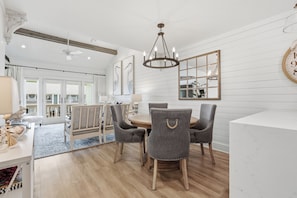 A dining area with a wooden table, four grey chairs, and a chandelier. - The Lady Cora | Canal Views + Community Pool (Rockport)