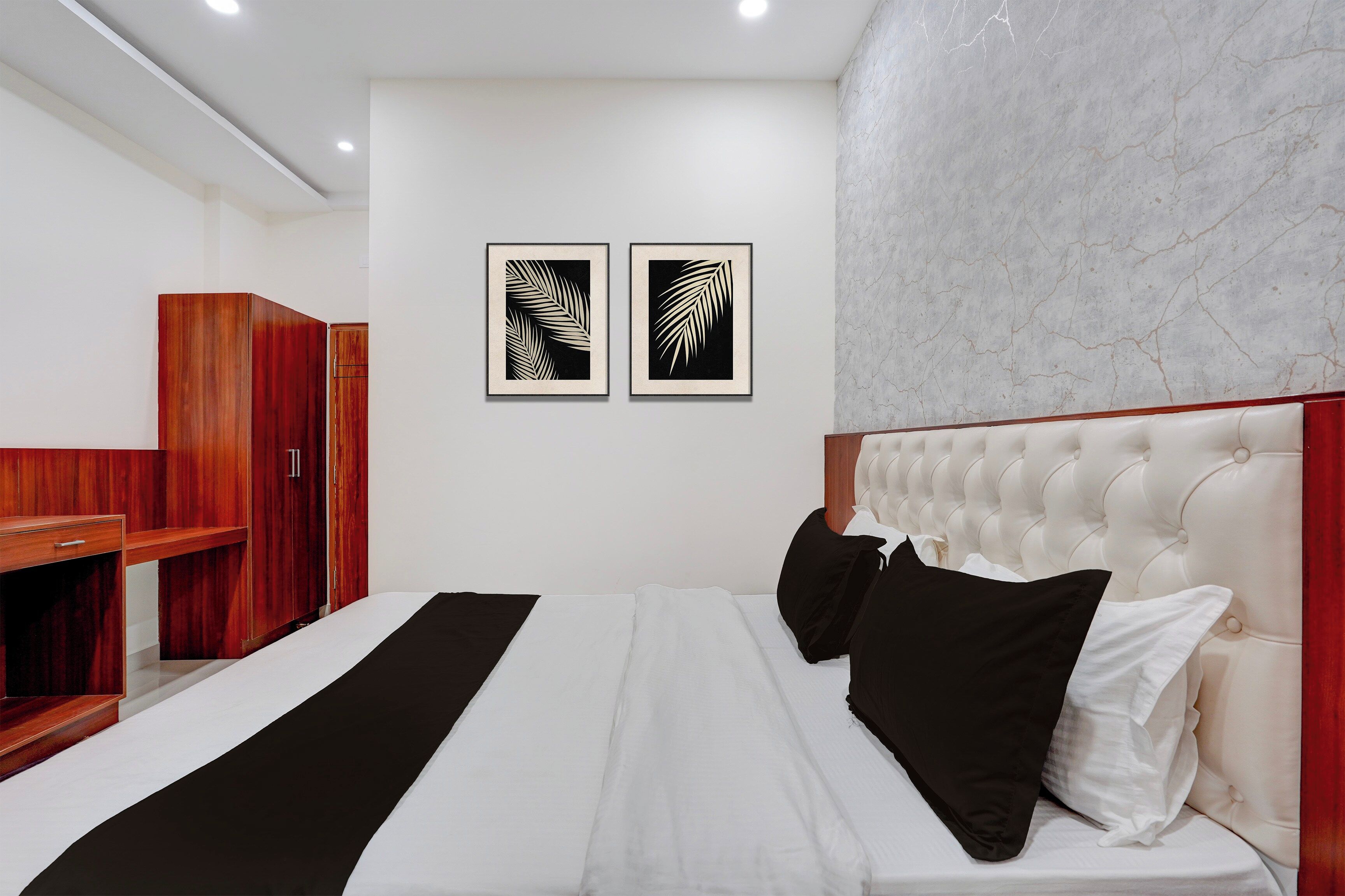 Un dormitorio con cama, armario y dos motivos de hojas enmarcados en la pared.