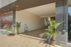 A building entrance with a 'NO PARKING' sign, potted plants, and a tiled floor.