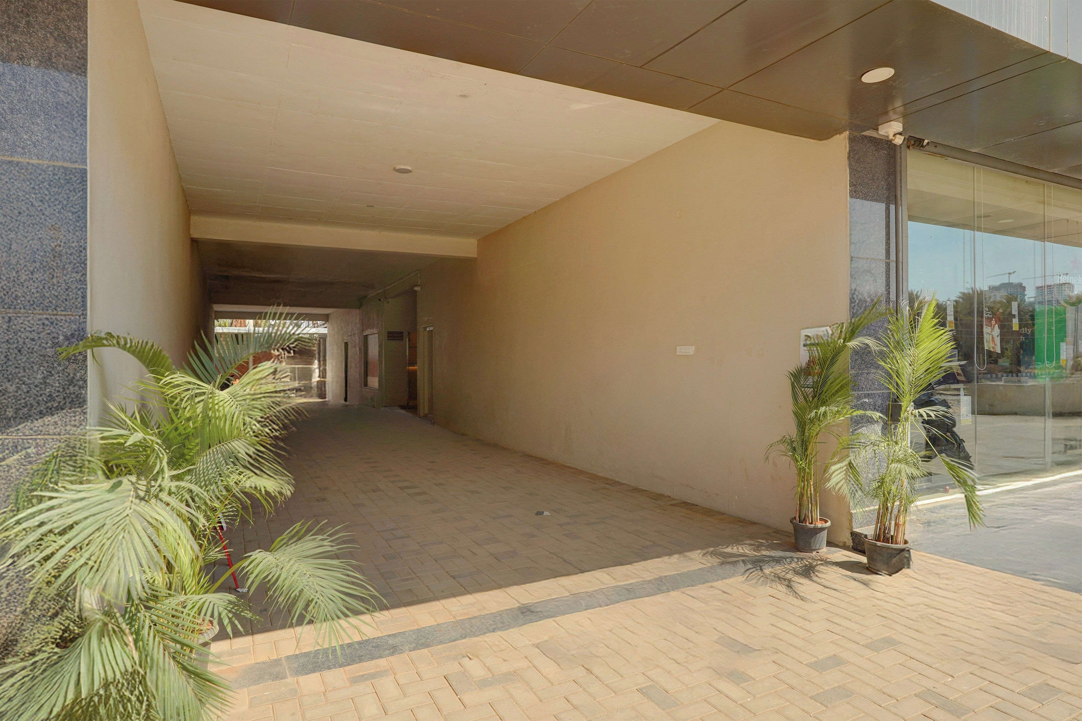 A corridor with a tiled floor, potted plants, and a glass entrance.