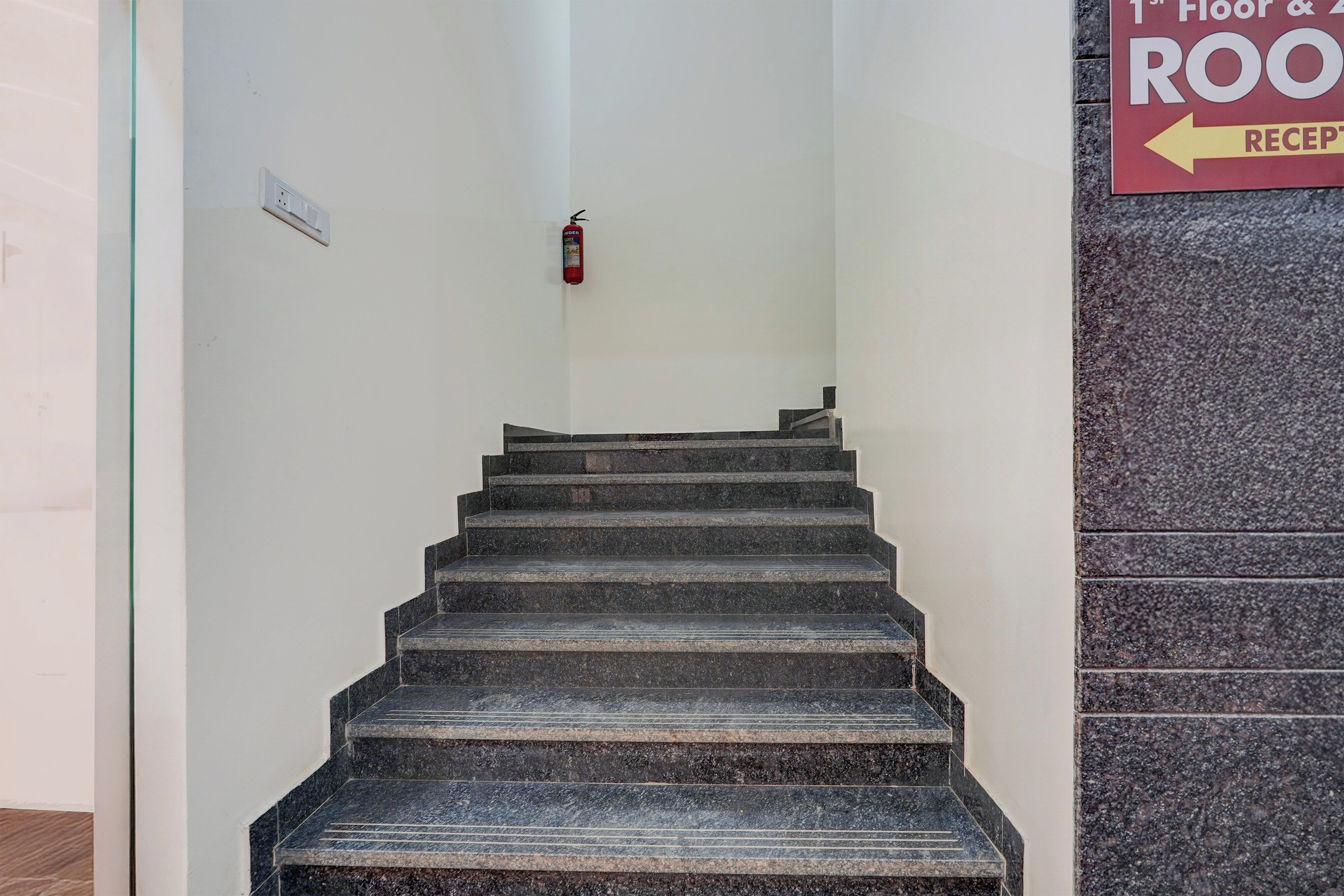 A staircase leading to the 1st floor with a reception sign on the right.