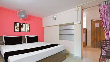 Una habitación de hotel con una cama, un ventilador de pared, una puerta con un letrero y una ventana con cortinas.
