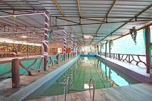 An indoor swimming pool with a wooden deck, metal railings, and a colorful wall mural. - Super Hotel O Ranihati Kolkata (Howrah)