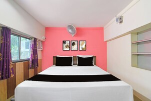 A room with a bed, a window with curtains, and three framed pictures on the wall.