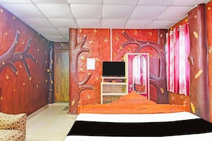 A bedroom with a bed, a TV, a wardrobe, and a door with a sign.