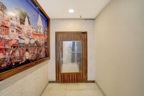 Um corredor com uma porta de madeira e uma grande moldura com uma imagem na parede.