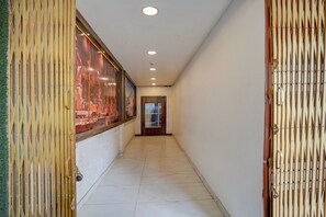 Un passadís amb terra de rajola, portes de fusta i un quadre encadre on la paret.