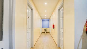 Un pasillo con suelo de madera, puertas blancas y una pared azul al final.