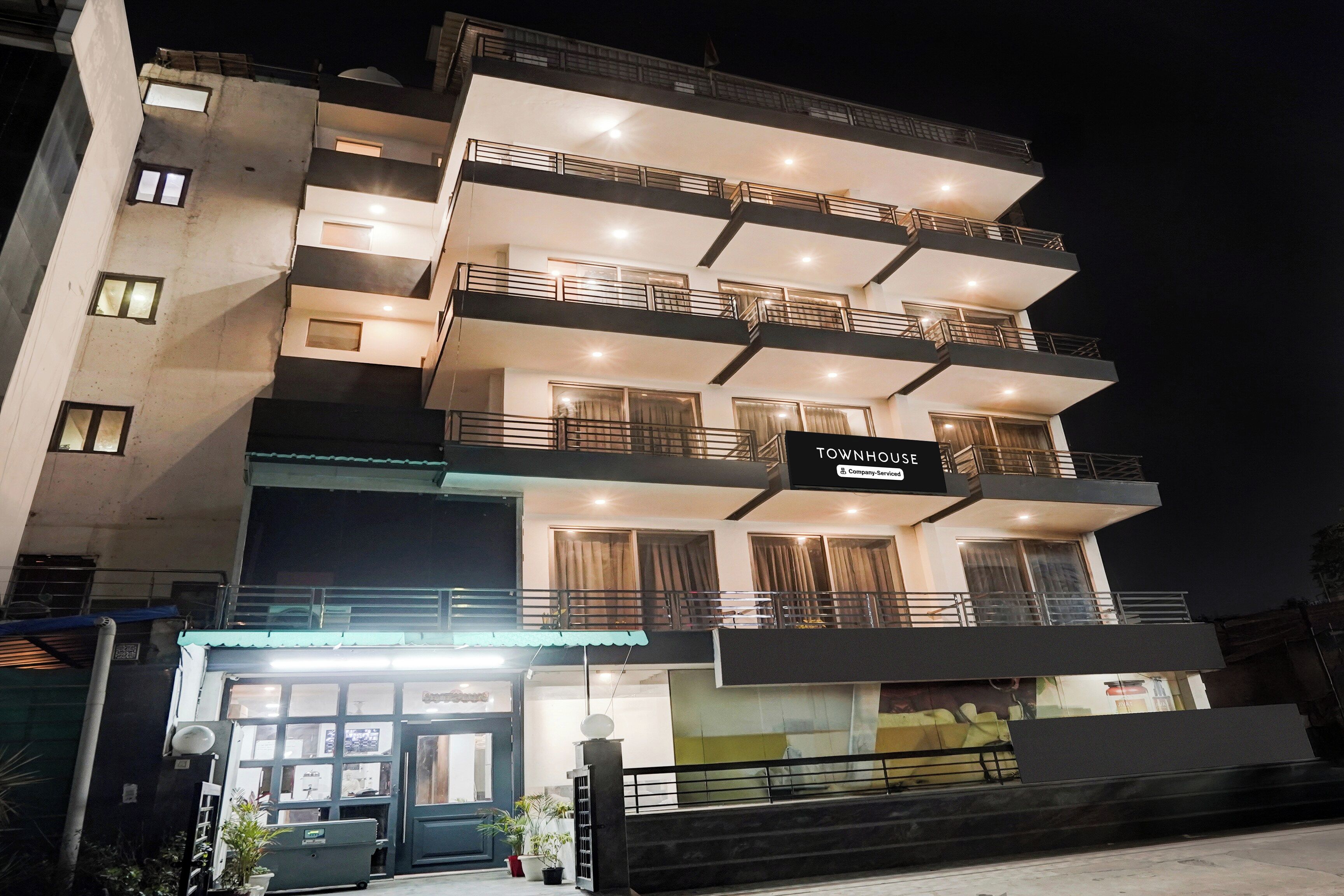 Un edificio de varios pisos con balcones, un letrero que indica que es una casa adosada y una entrada con portón.