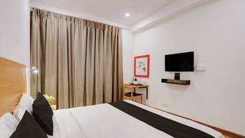Habitación de hotel con cama, escritorio con silla, televisor y un cuadro en la pared.