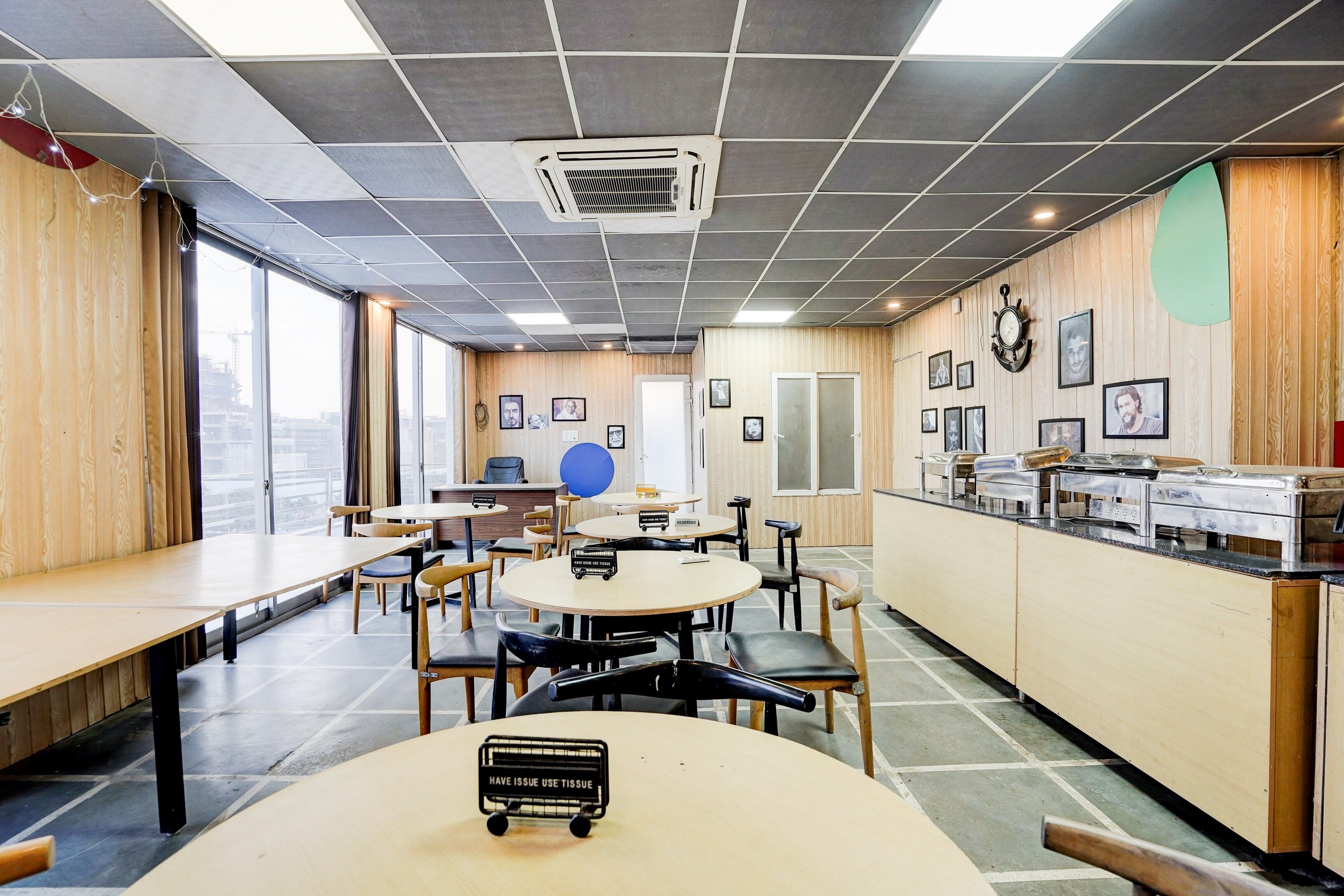 Un comedor moderno con mesas redondas, sillas y una barra de buffet.