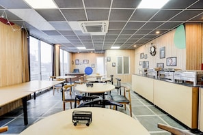 A modern dining area with round tables, chairs, and a buffet counter. - Townhouse Sector 39 Gurgaon (Gurugram)