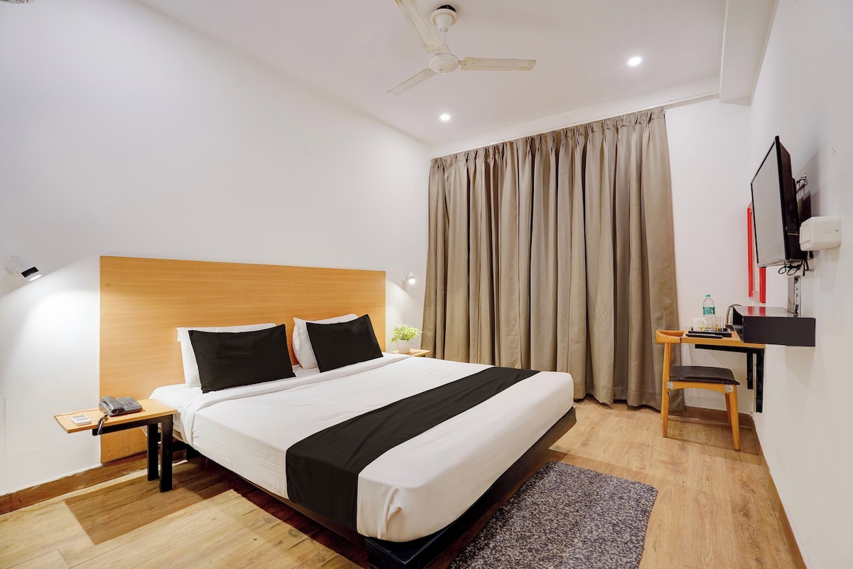 A hotel room with a bed, bedside table, desk, chair, and a ceiling fan.