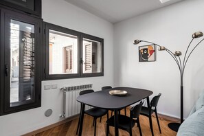 Zona pranzo moderna con tavolo rotondo, sedie nere, una lampada da terra e un termosifone.