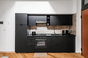 A modern kitchen with black cabinetry, a stainless steel oven, and a built-in stove. - New Listing (Roma)