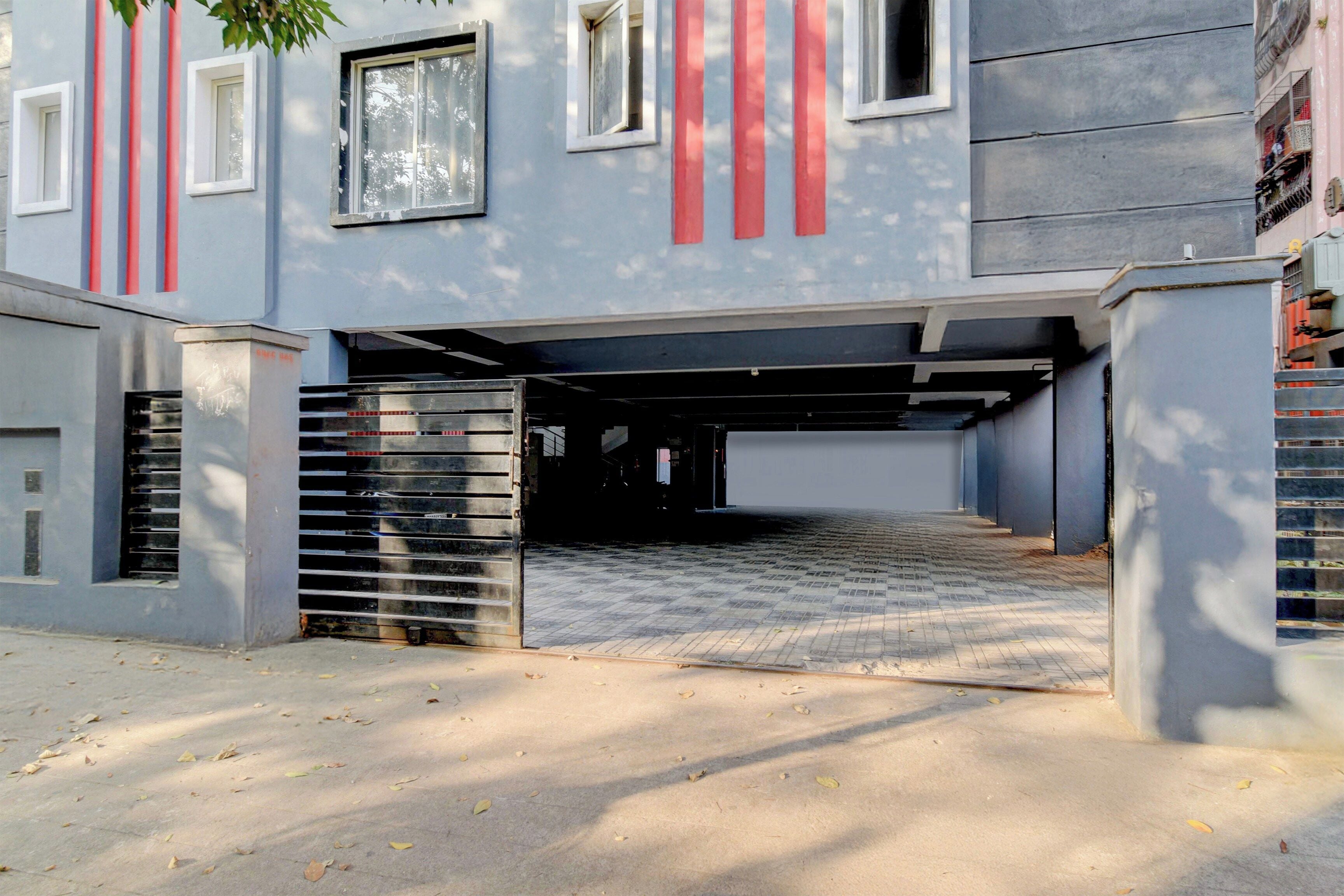 A building with a covered parking area, a gated entrance, and a paved driveway.