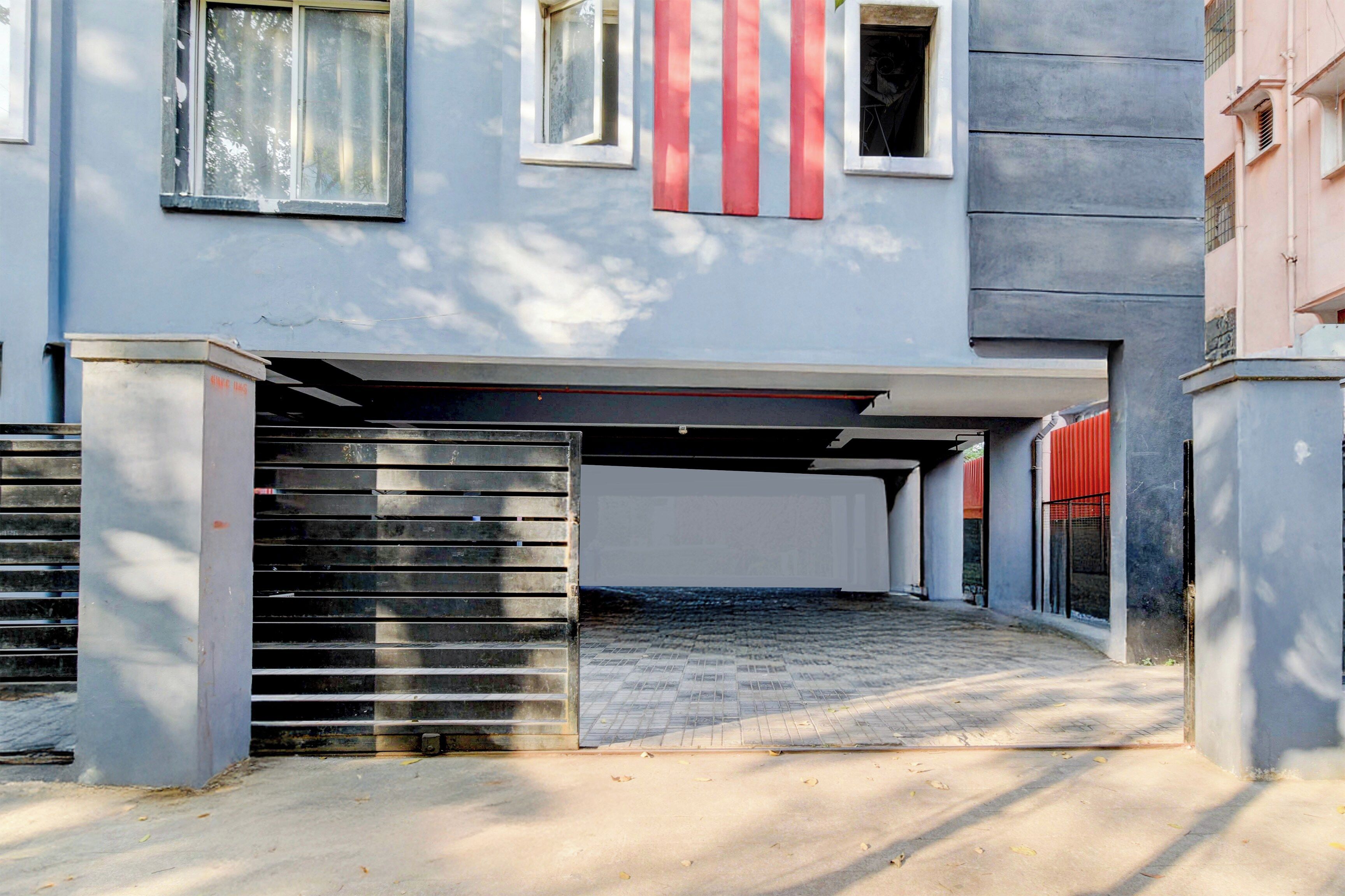 Ein Gebäude mit überdachtem Parkbereich, befahrtsbeschränkter Einfahrt und blauem Himmel.