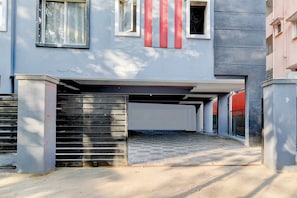 Un edificio con estacionamiento techado, entrada protegida por un portón y cielo despejado.
