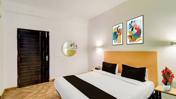 Une chambre d’hôtel comprenant un lit, une table de chevet avec un vase et deux œuvres d’art accrochées au mur.