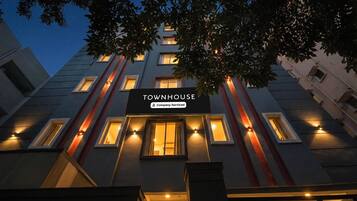 Un immeuble à plusieurs étages, doté de fenêtres illuminées et d’une enseigne indiquant : « TOWNHOUSE, services d’entreprise ».