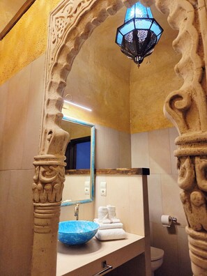 A bathroom with a blue basin, a mirror, and a decorative archway. - New Listing (Orgaz)