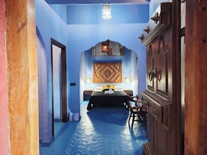 A room with a bed, a nightstand, a lamp, and a wall-mounted tapestry. - New Listing (Orgaz)