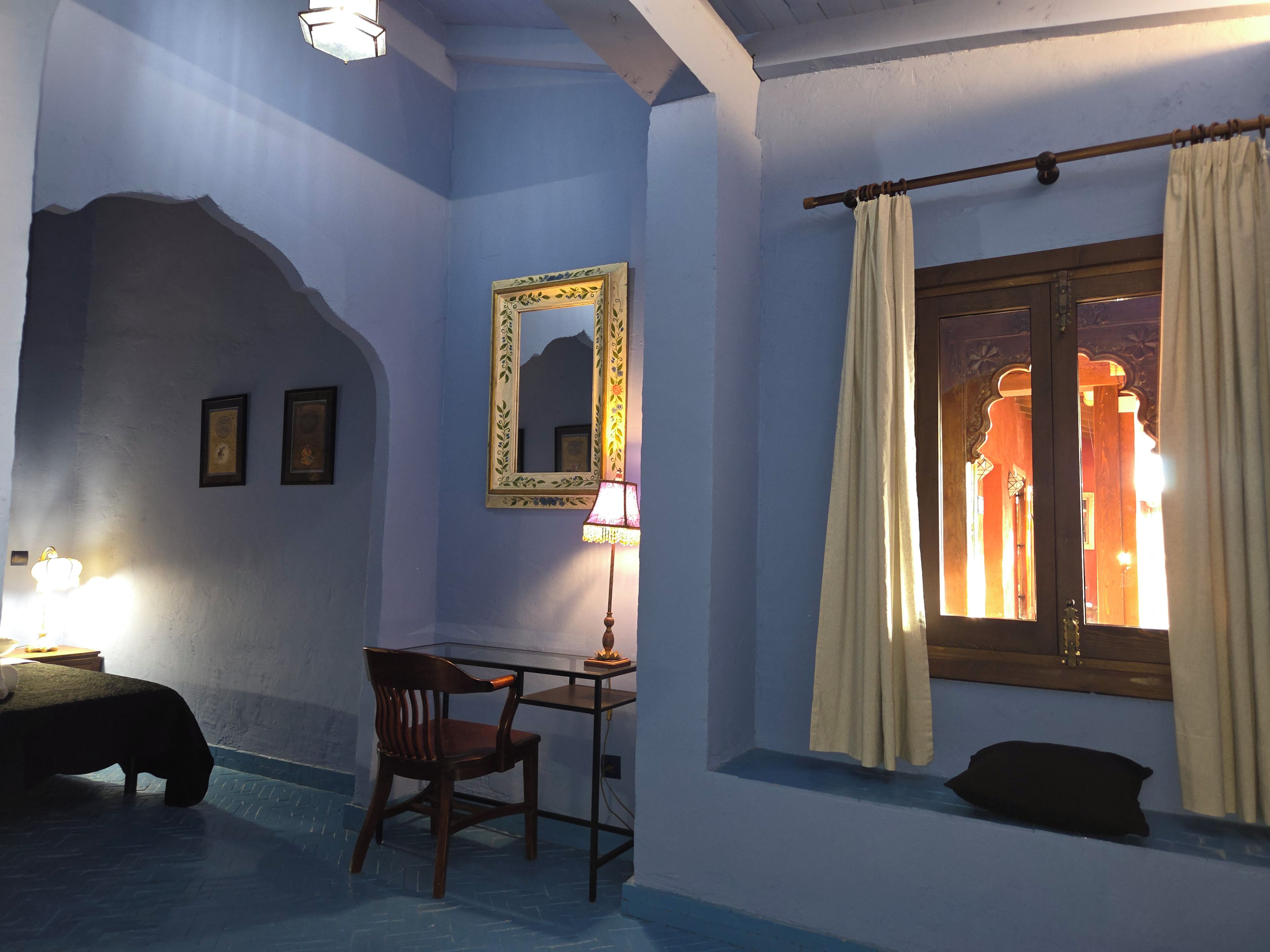 Una habitación con un escritorio, una silla y un espejo grande en la pared.
