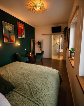 A bedroom with a bed, two chairs, a TV, and artwork on the wall. - New Listing (Magdeburg)