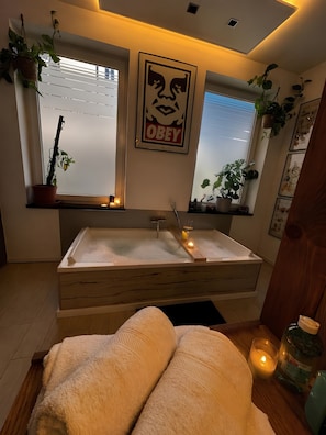 A modern bathroom with a freestanding bathtub, potted plants, and a framed artwork on the wall. - New Listing (Magdeburg)