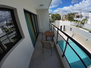A balcony with a pool, a table, and two chairs. - Charming Bayahíbe Apartment Comfort Pool, Beach Access (San Rafael del Yuma)
