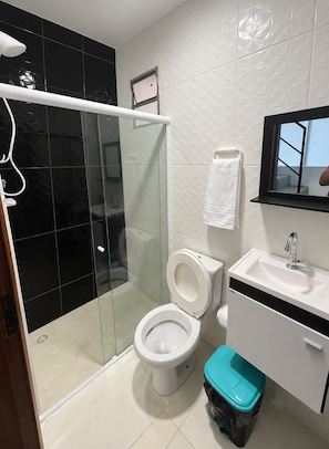 Ein modernes Badezimmer mit Glasdusche, Toilette, Waschbecken und Spiegel.