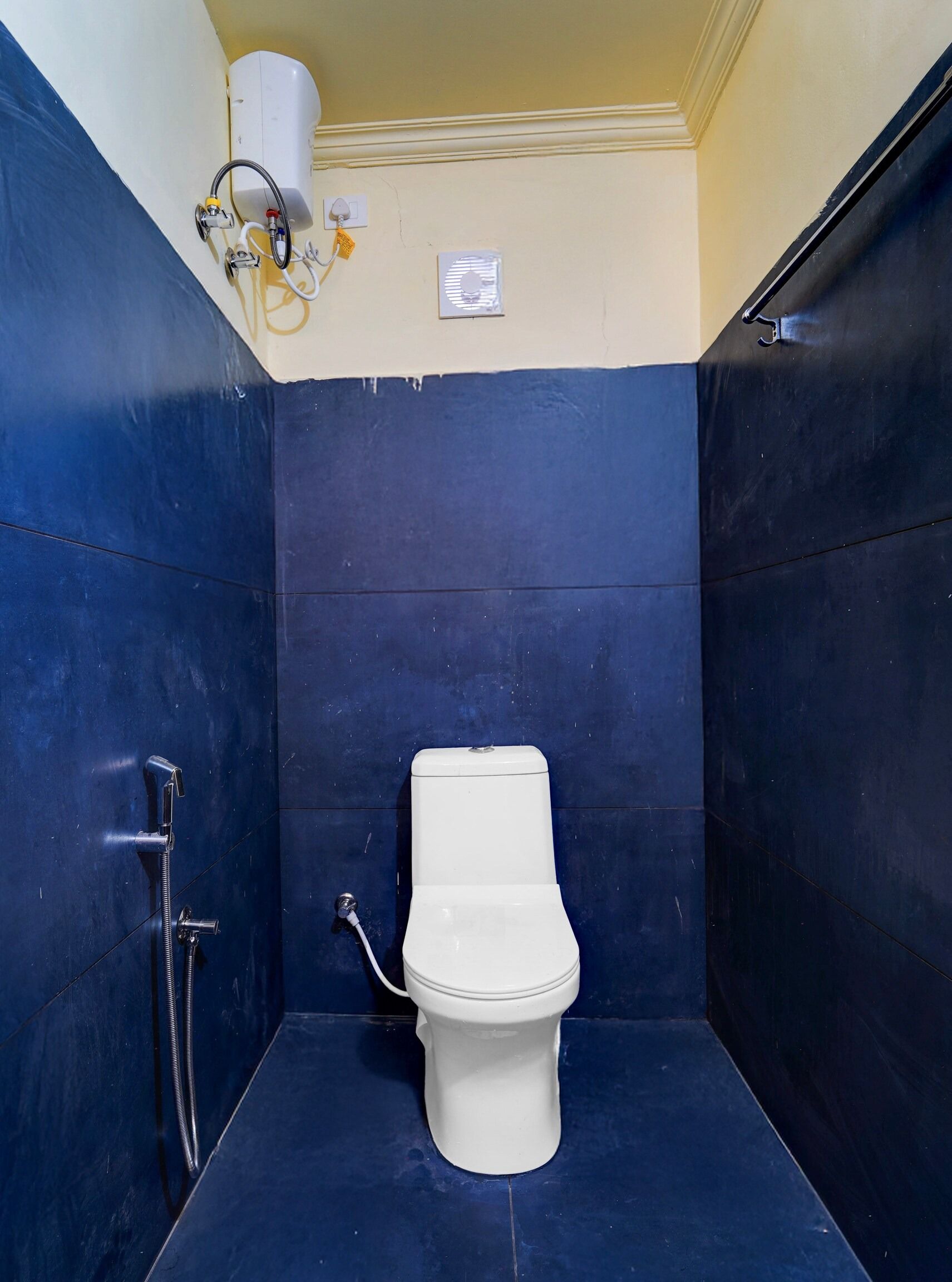 Un baño pequeño y cerrado con inodoro, ducha y un calentador de pared.