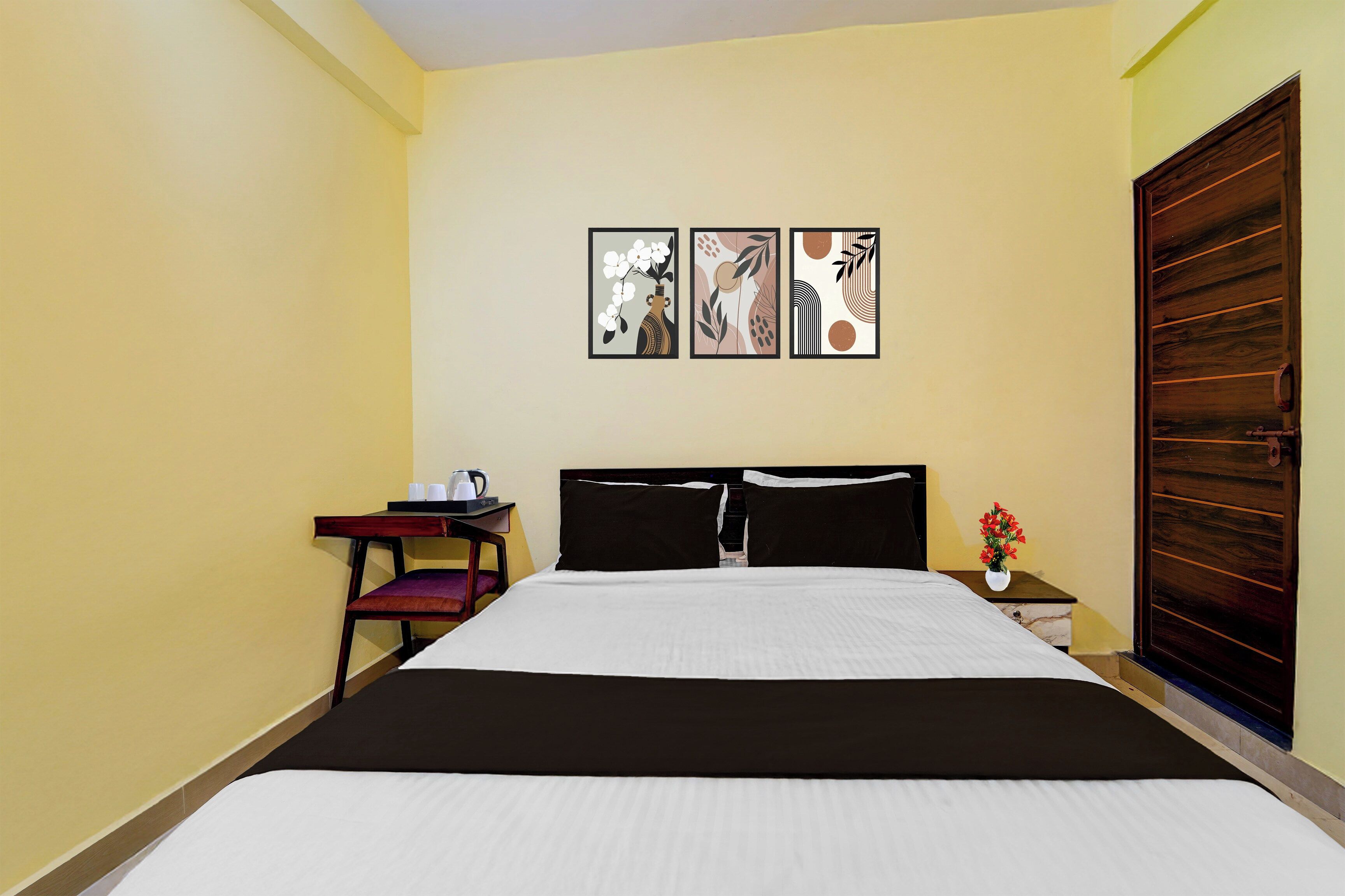 Una habitación de hotel con cama, mesita de noche, una silla y una puerta de madera.
