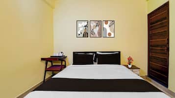 Una habitación de hotel con cama, mesita de noche, una silla y una puerta de madera.