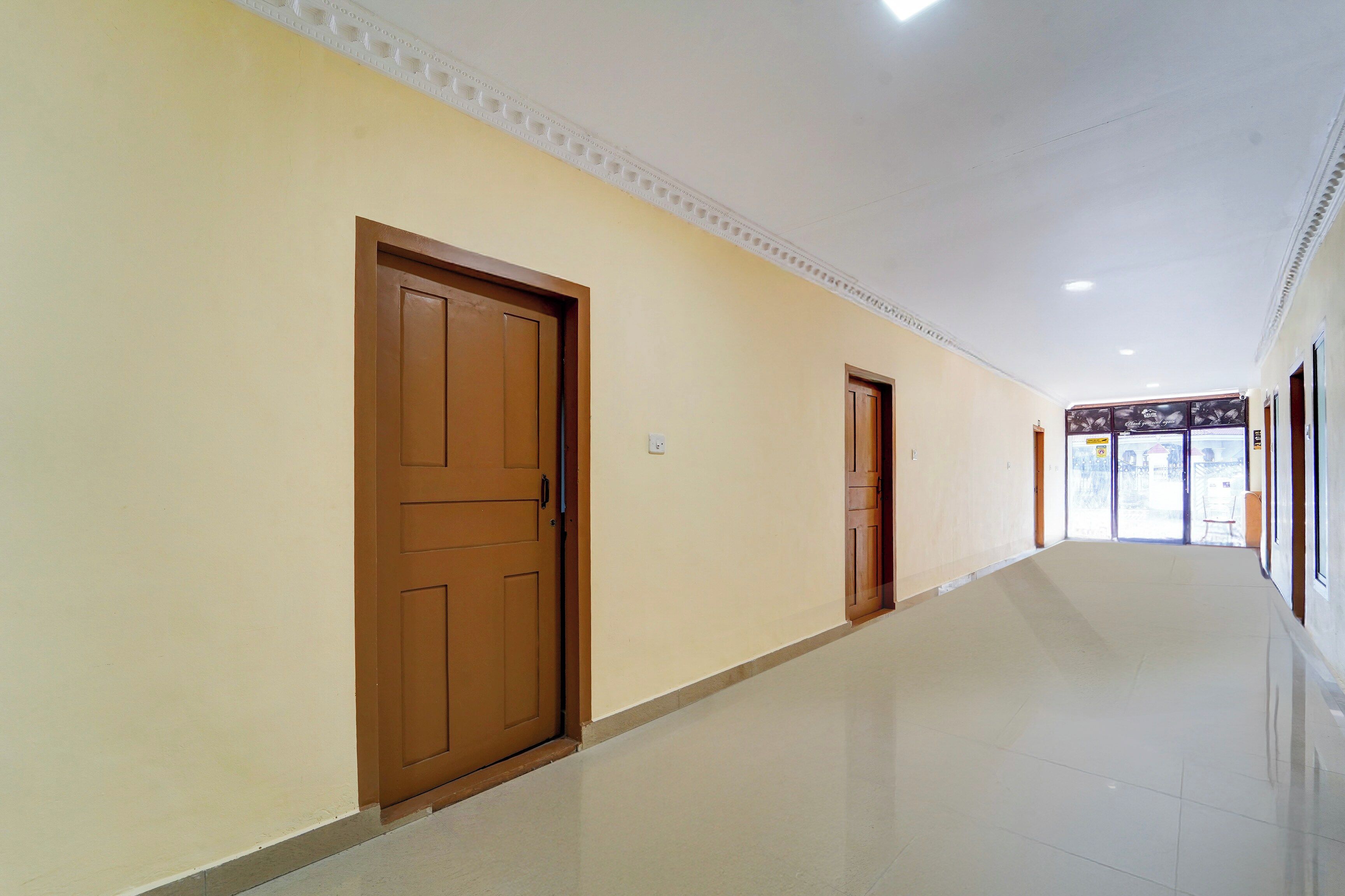 A corridor with two wooden doors, white walls, and a tiled floor.