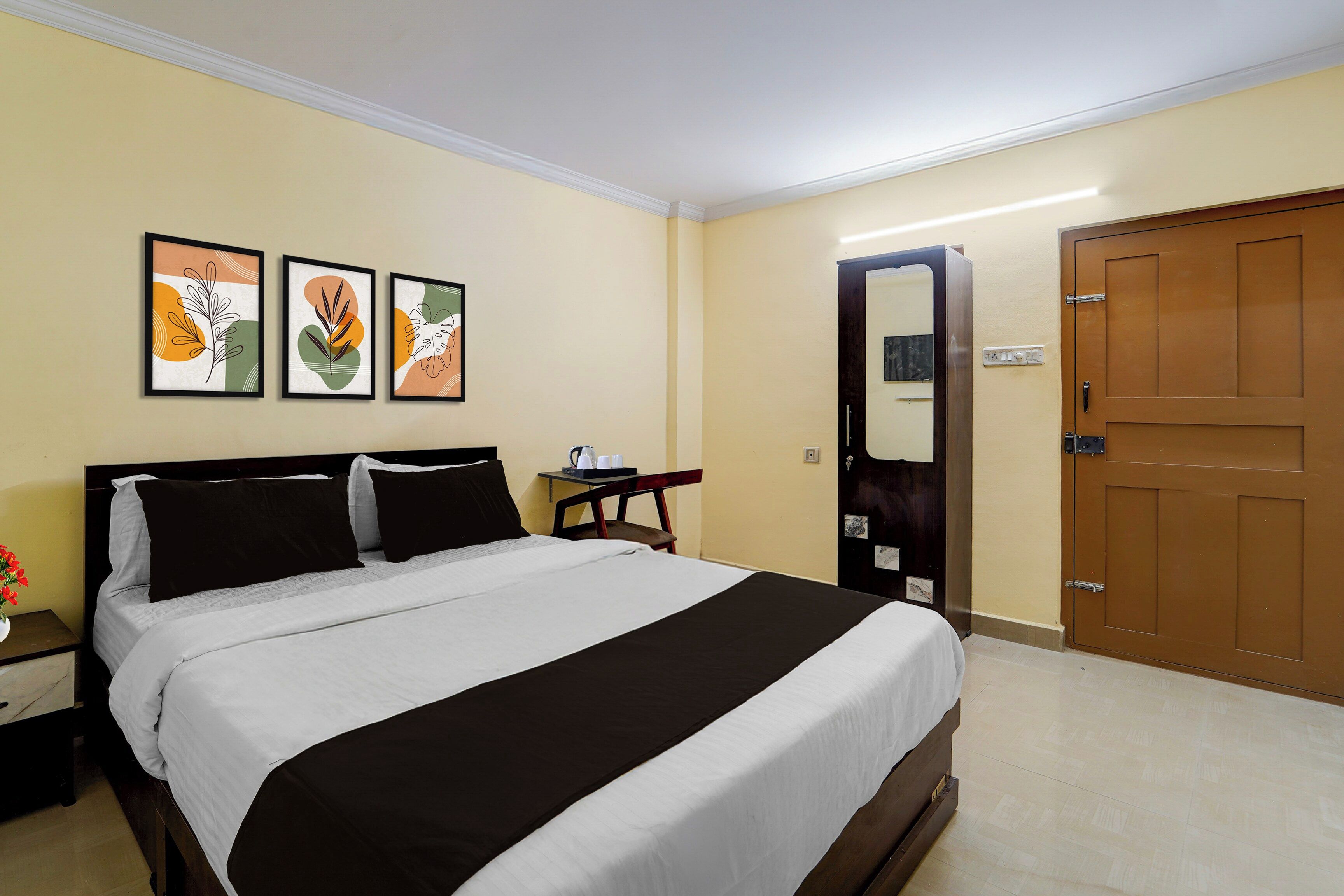 Una habitación de hotel con una cama, una mesita de noche, una pequeña mesa con una bandeja y una puerta.