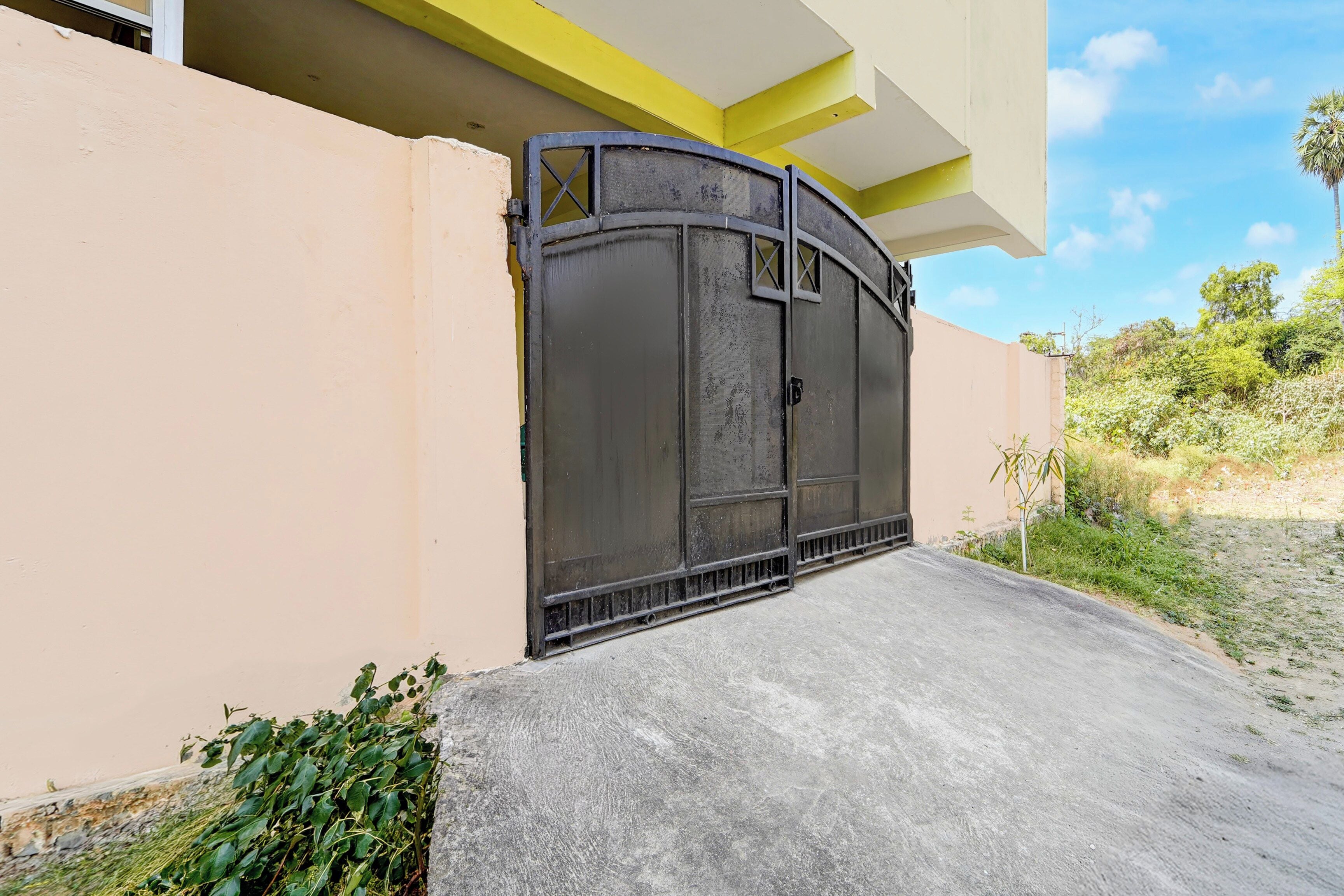 A gated entrance with a concrete ramp leading up to a building with a yellow and white facade.