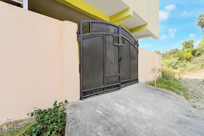 A gated entrance with a concrete ramp leading up to a building with a yellow and white facade.