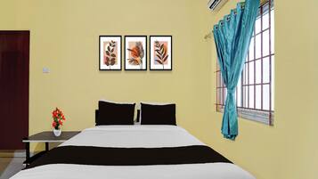 Un dormitorio con una cama, una mesita de noche, un florero con flores y tres cuadros en la pared.
