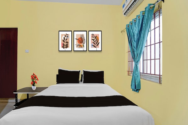 A bedroom with a bed, a nightstand, a vase with flowers, and three framed pictures on the wall. - Hotel O Narsampathi Lakeview Coimbatore (Coimbatore)