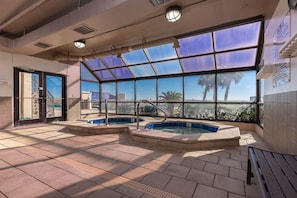 A rooftop pool area with two hot tubs, large windows, and a view of palm trees. - Phoenix East 1508 1 Bedroom Condo (Orange Beach)