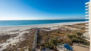 A beach view with a wooden boardwalk leading to a building with balconies. - Phoenix East 605 1 Bedroom Condo (Orange Beach)