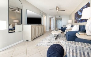 A modern living room with a flat-screen TV, a sofa, a coffee table, and a patterned rug. - Phoenix East 605 1 Bedroom Condo (Orange Beach)