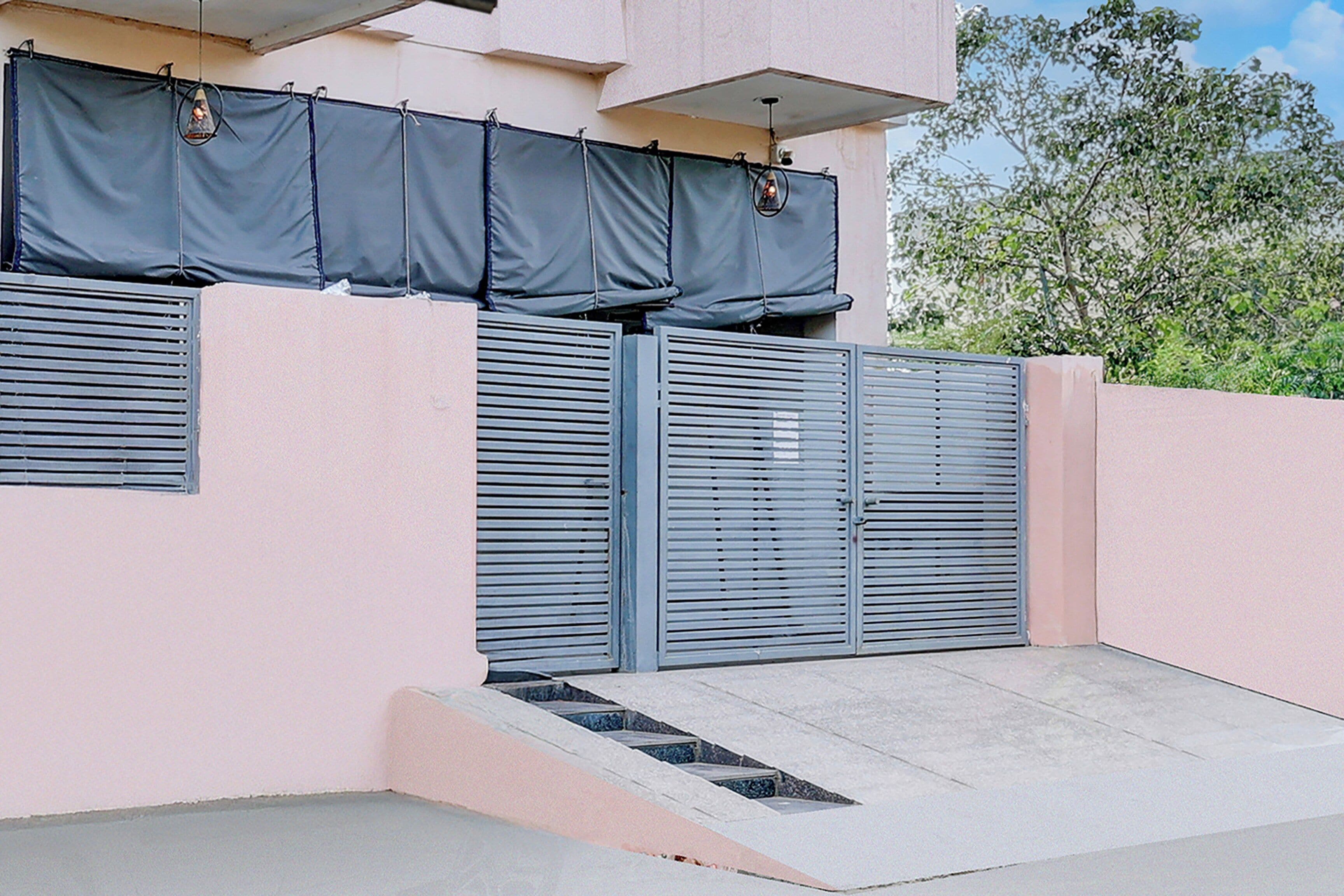 A building with a pink exterior, a gated entrance, and a small concrete staircase leading up to the gate.