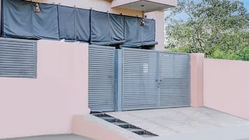 A building with a pink exterior, a gated entrance, and a small concrete staircase leading up to the gate.