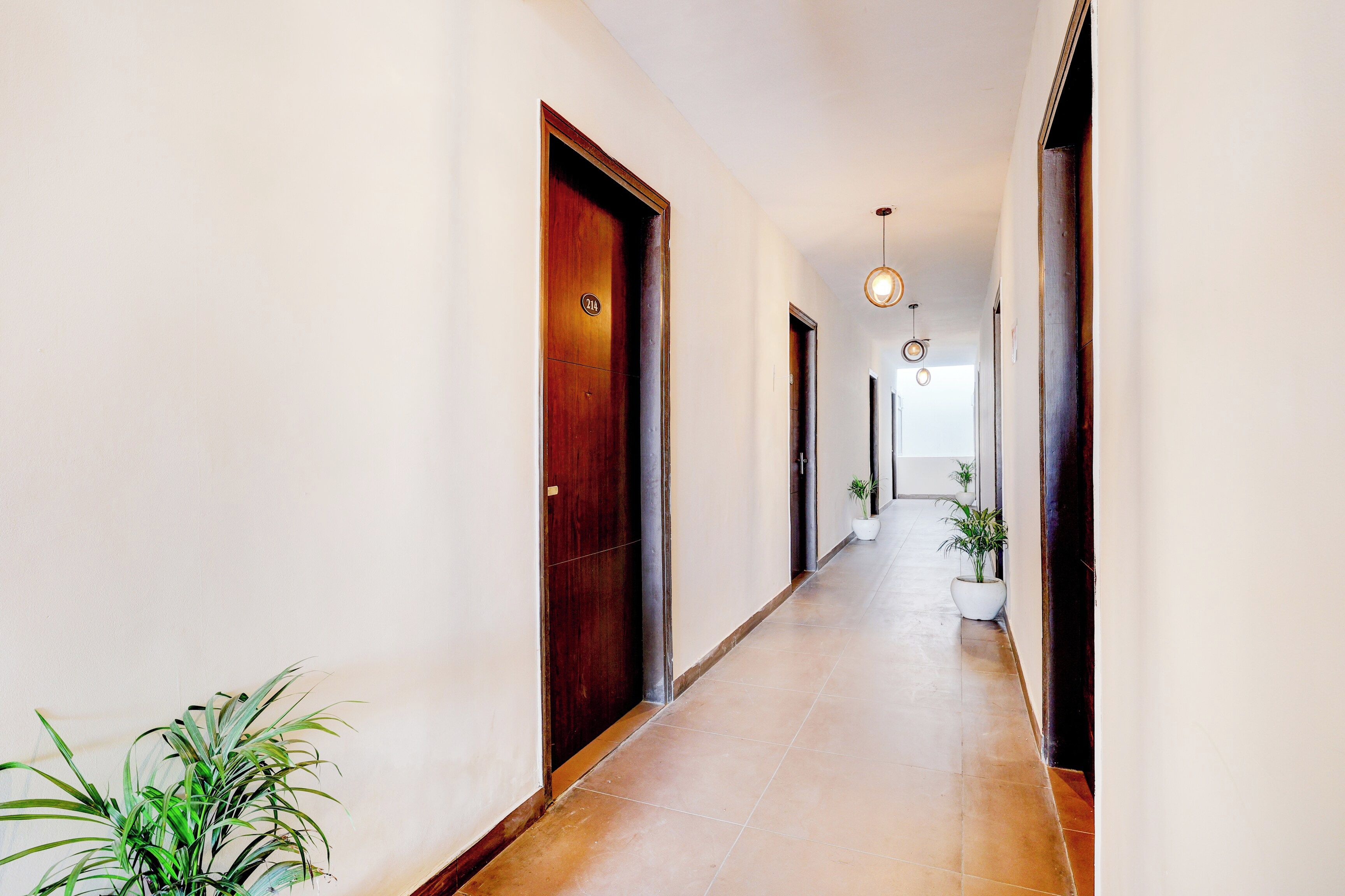 A hallway with wooden doors, a tiled floor, and hanging pendant lights.