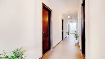 A hallway with wooden doors, a tiled floor, and hanging pendant lights.