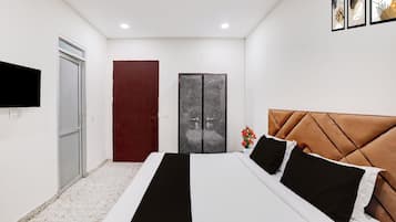 A bedroom with a bed, a TV mounted on the wall, a door, and a wall-mounted artwork.