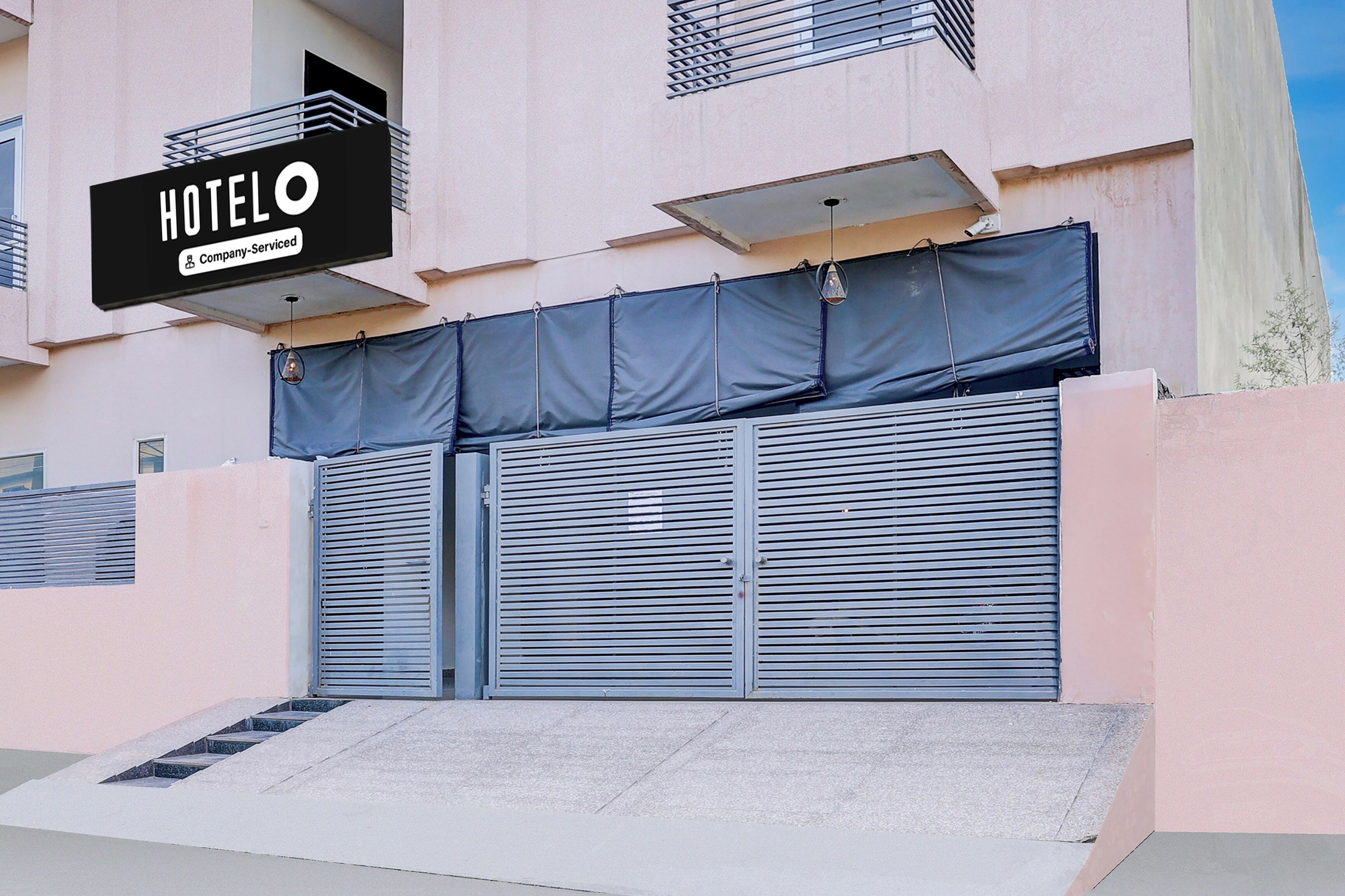 L’entrée d’un hôtel, avec un volet fermé, une enseigne et un escalier menant à l’étage.